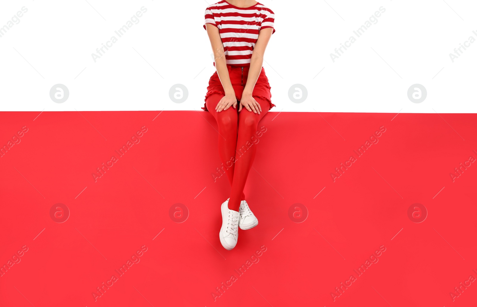 Photo of Woman wearing red tights and stylish shoes sitting on color background, closeup