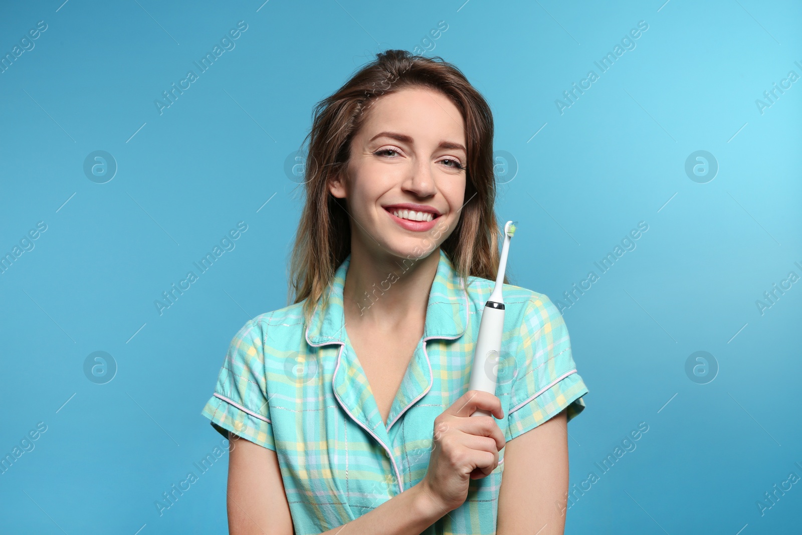 Photo of Portrait of young woman with electric toothbrush on color background