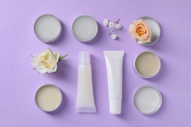 Flat lay composition with lip balms and flowers on lilac background