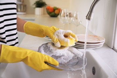 Photo of Woman washing plate above sink in kitchen, closeup