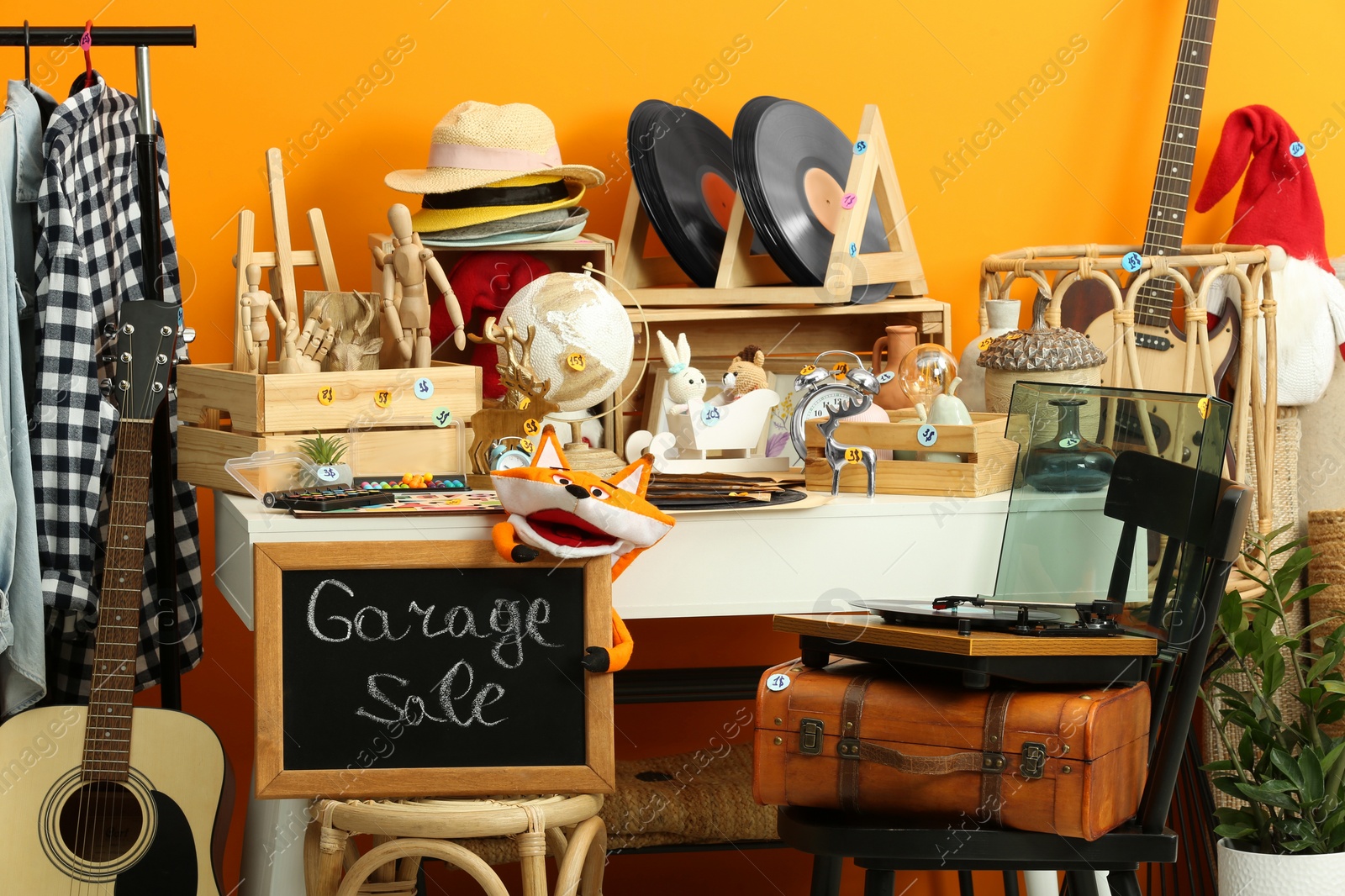 Photo of Sign Garage Sale written on blackboard near many different stuff