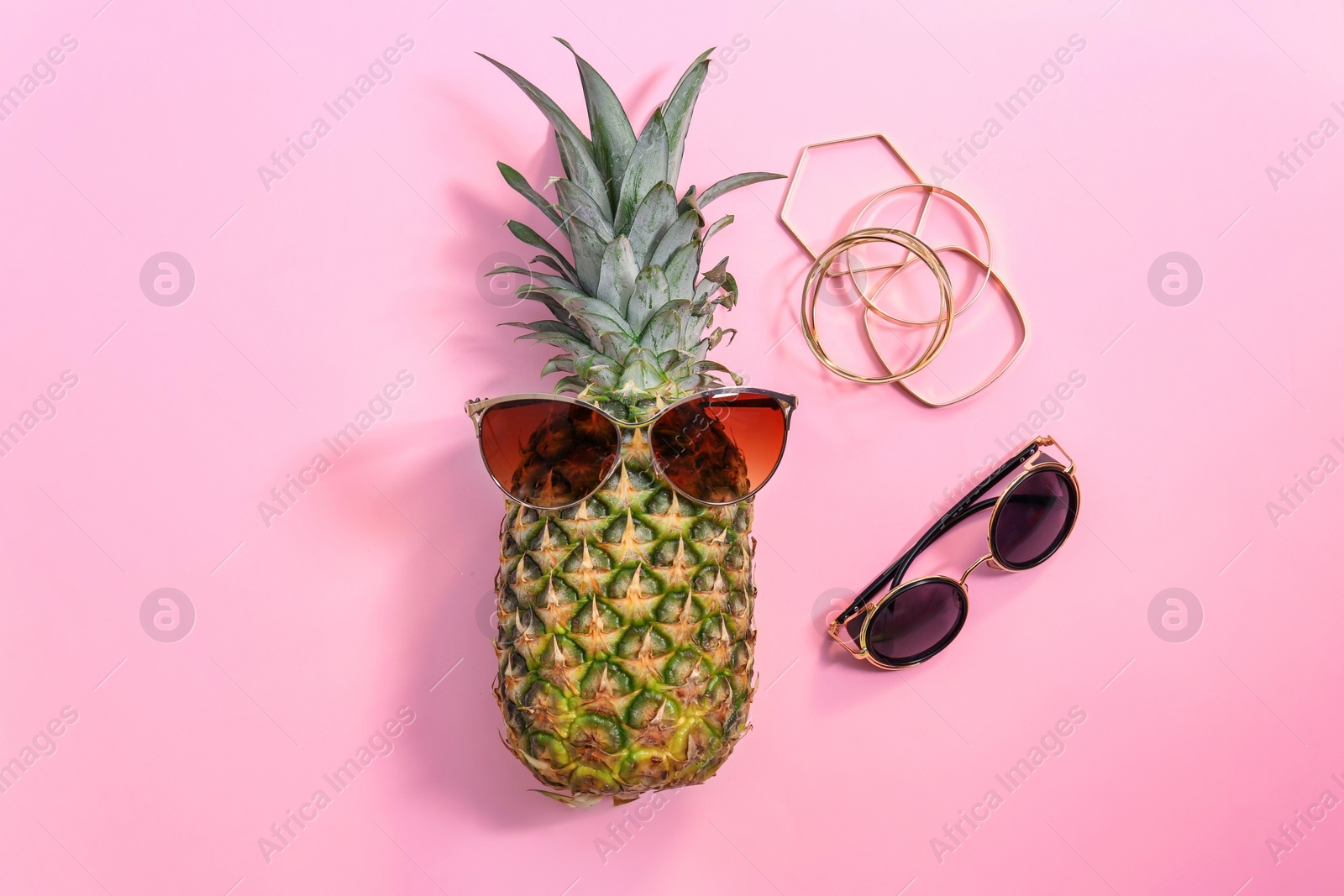 Photo of Fresh ripe pineapple with sunglasses on color background, top view