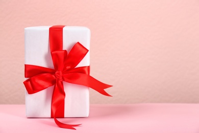 Photo of Beautiful gift box on table against color background