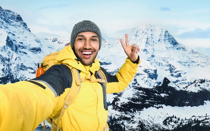 Image of Happy tourist with backpack taking selfie in snowy mountains