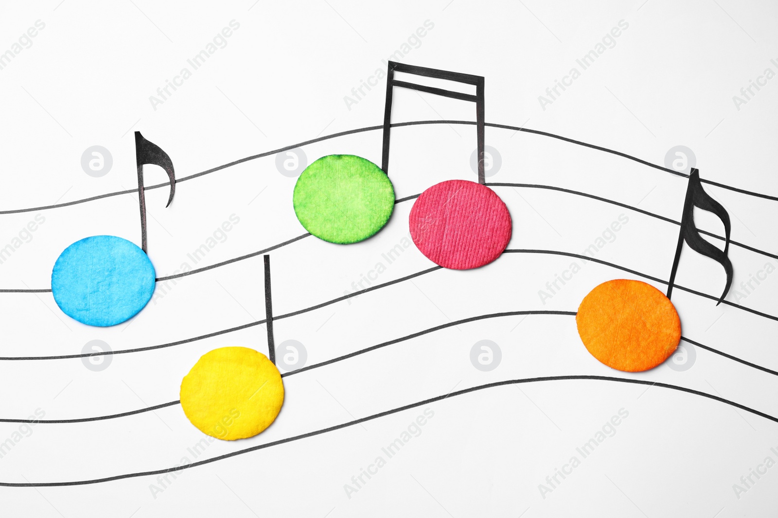 Photo of Dyed cotton pads as musical notes on white background, flat lay