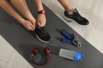 Top view of man tying shoelaces on yoga mat