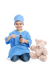 Cute child playing doctor with stuffed toy on white background