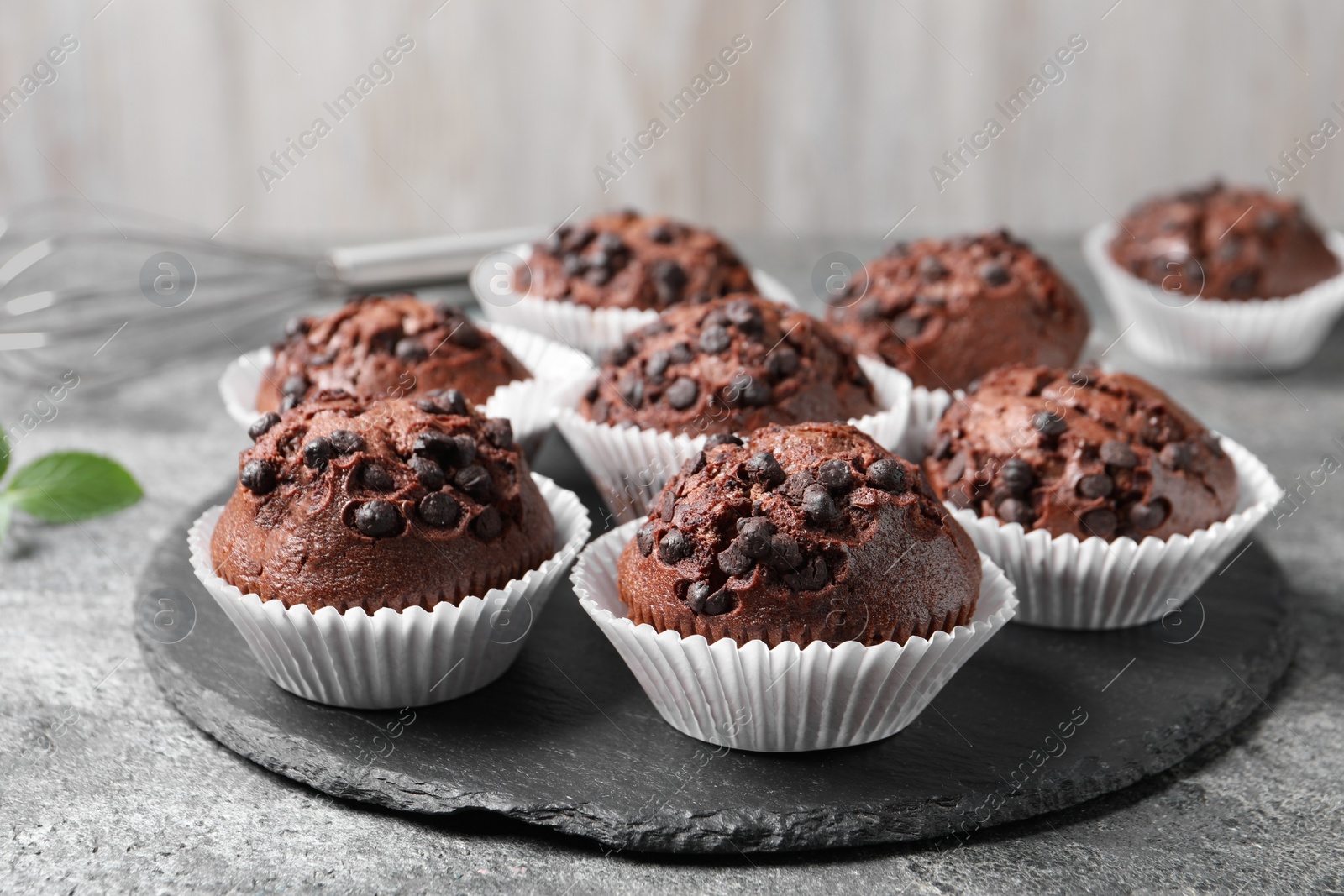 Photo of Tasty chocolate muffins on grey textured table, closeup