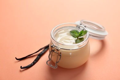 Jar with vanilla pudding, sticks and fresh mint on color background