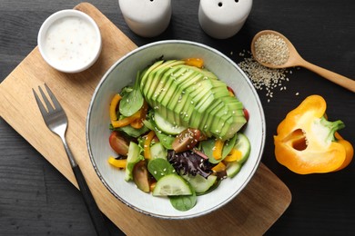 Photo of Healthy dish high in vegetable fats served on black wooden table, flat lay