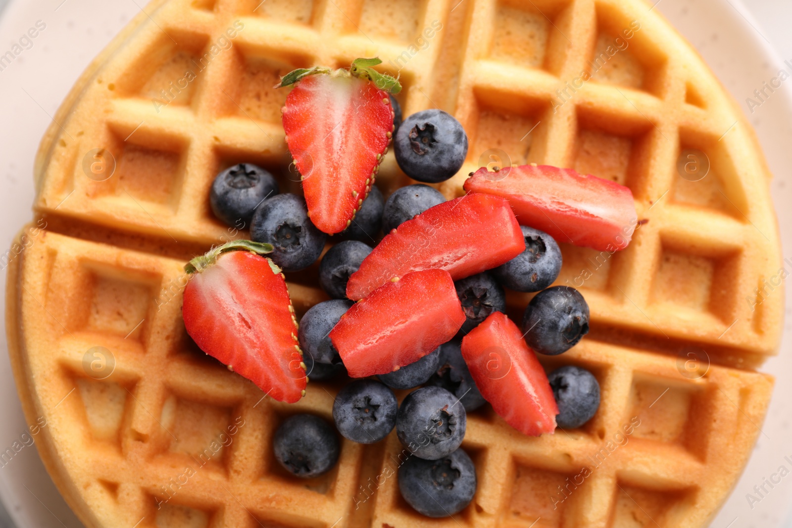 Photo of Tasty Belgian waffle with fresh berries on plate, top view