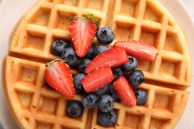 Tasty Belgian waffle with fresh berries on plate, top view