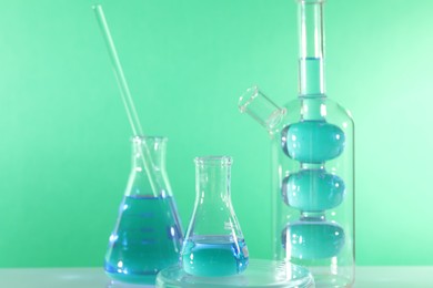 Photo of Laboratory analysis. Different glassware on table against green background