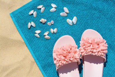Photo of Towel, seashells and flip flops on sand, top view. Beach accessories