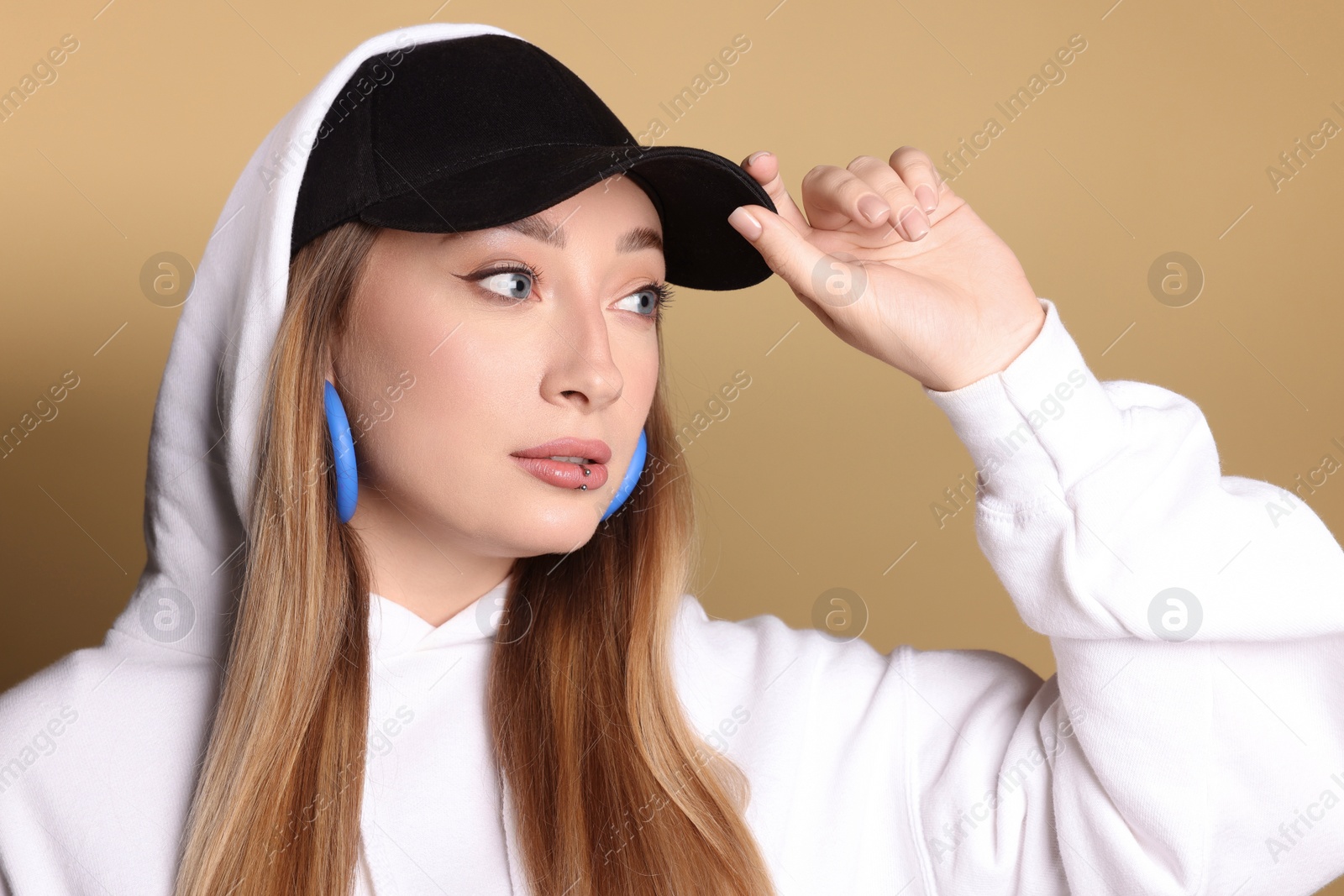 Photo of Young woman with lip piercing on beige background