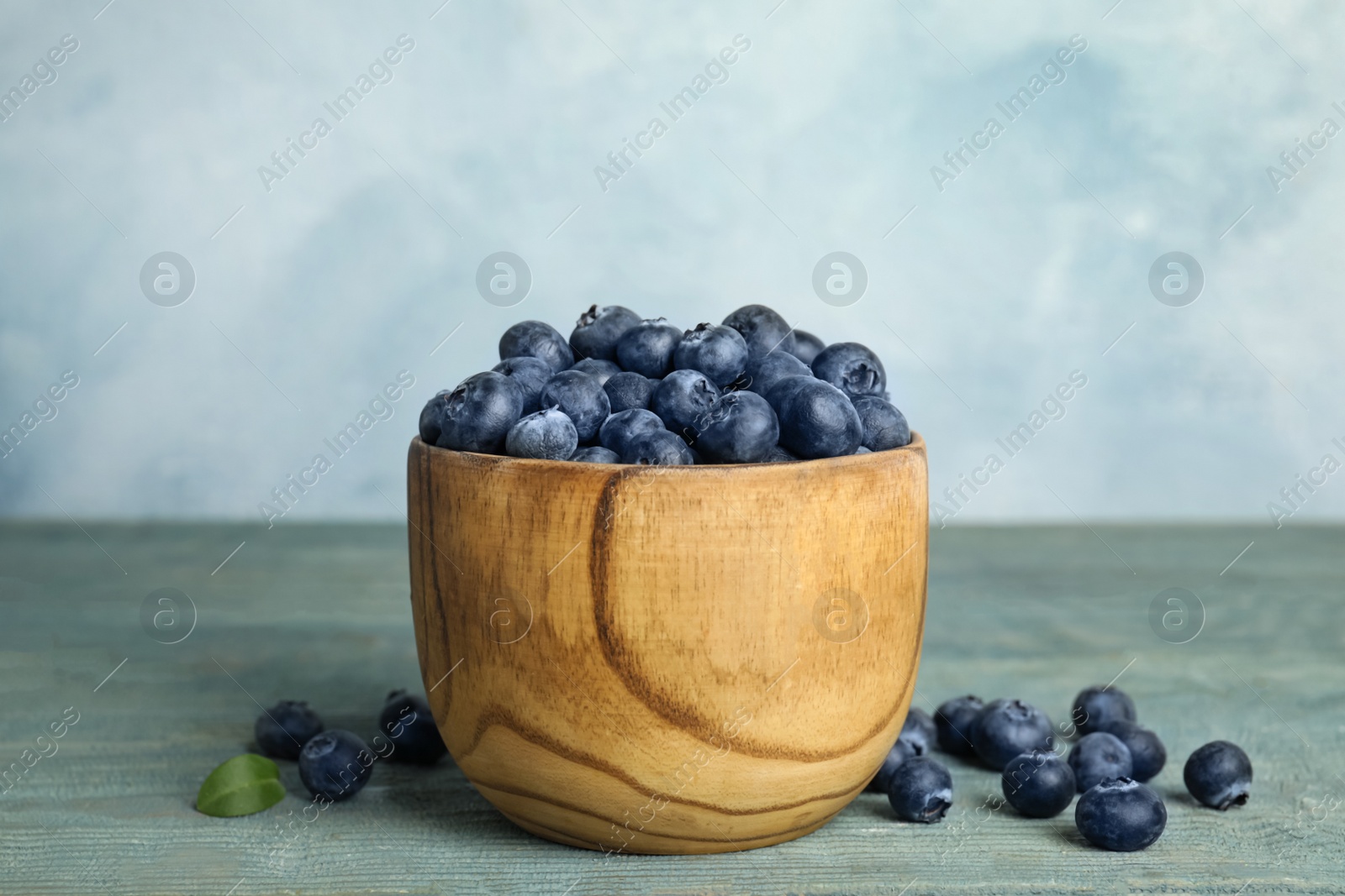 Photo of Fresh ripe blueberries in bowl on wooden table