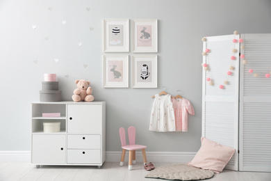 Photo of Stylish baby room interior with chest of drawers and cute pictures on wall