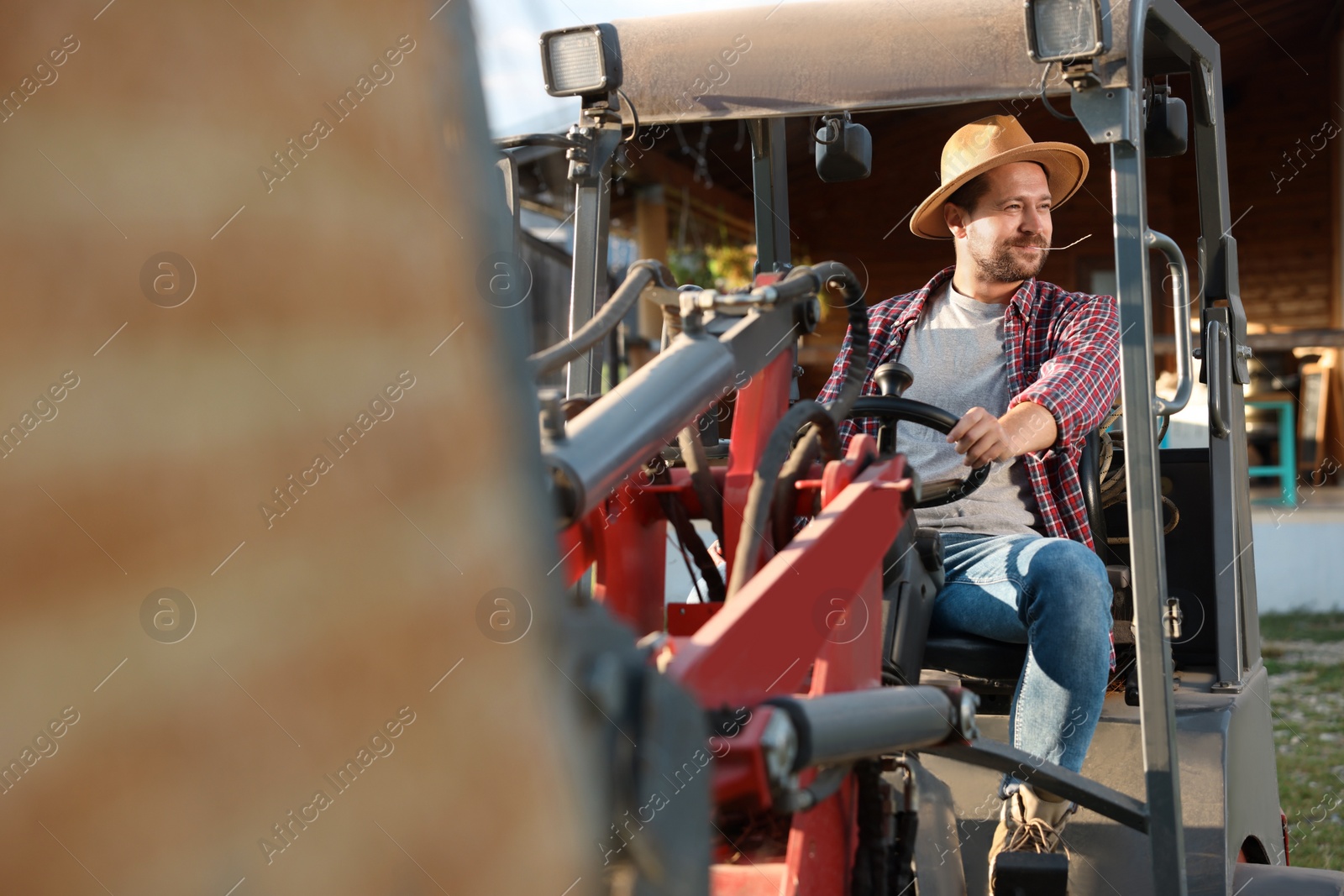 Photo of Farmer in loader transporting hay outdoors. Agriculture equipment