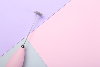 Pink milk frother wand on color background, top view. Space for text