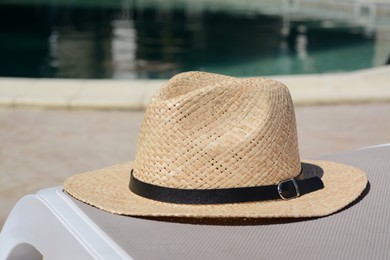 Photo of Stylish hat near outdoor swimming pool on sunny day. Beach accessory