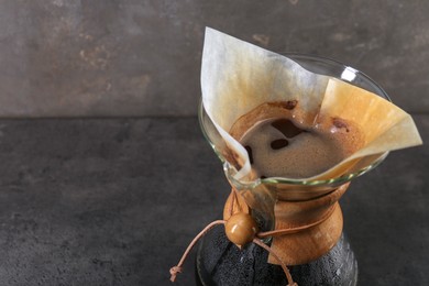 Photo of Glass chemex coffeemaker with coffee on gray table, closeup. Space for text