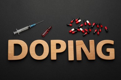 Word Doping of wooden letters with drugs on black background, flat lay