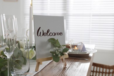 Photo of Festive table setting with floral decor and Welcome sign indoors