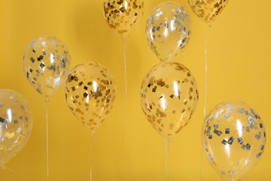 Bright balloons with ribbons on color background