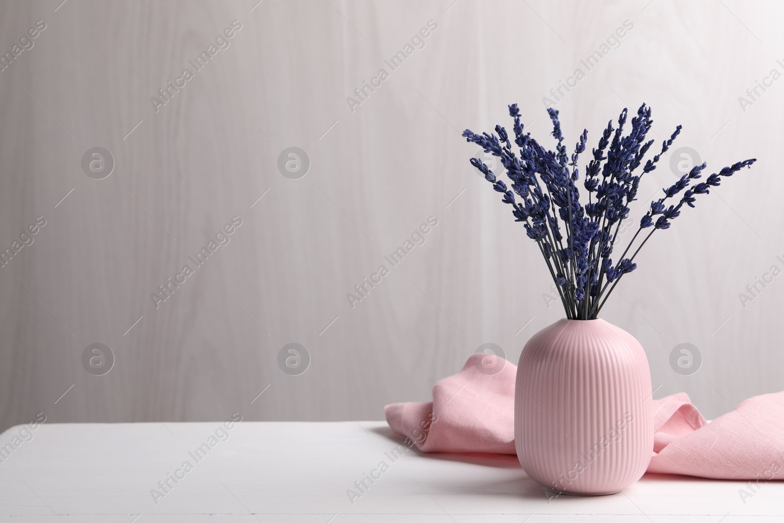 Photo of Bouquet of beautiful preserved lavender flowers on white wooden table near grey wall, space for text