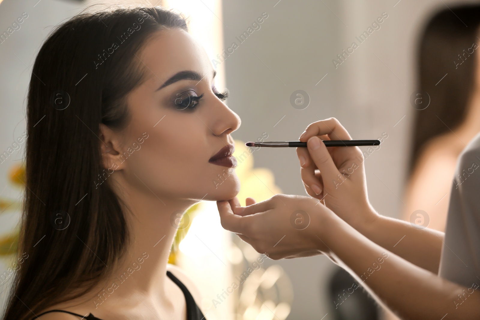 Photo of Professional visage artist applying makeup on woman's face in salon