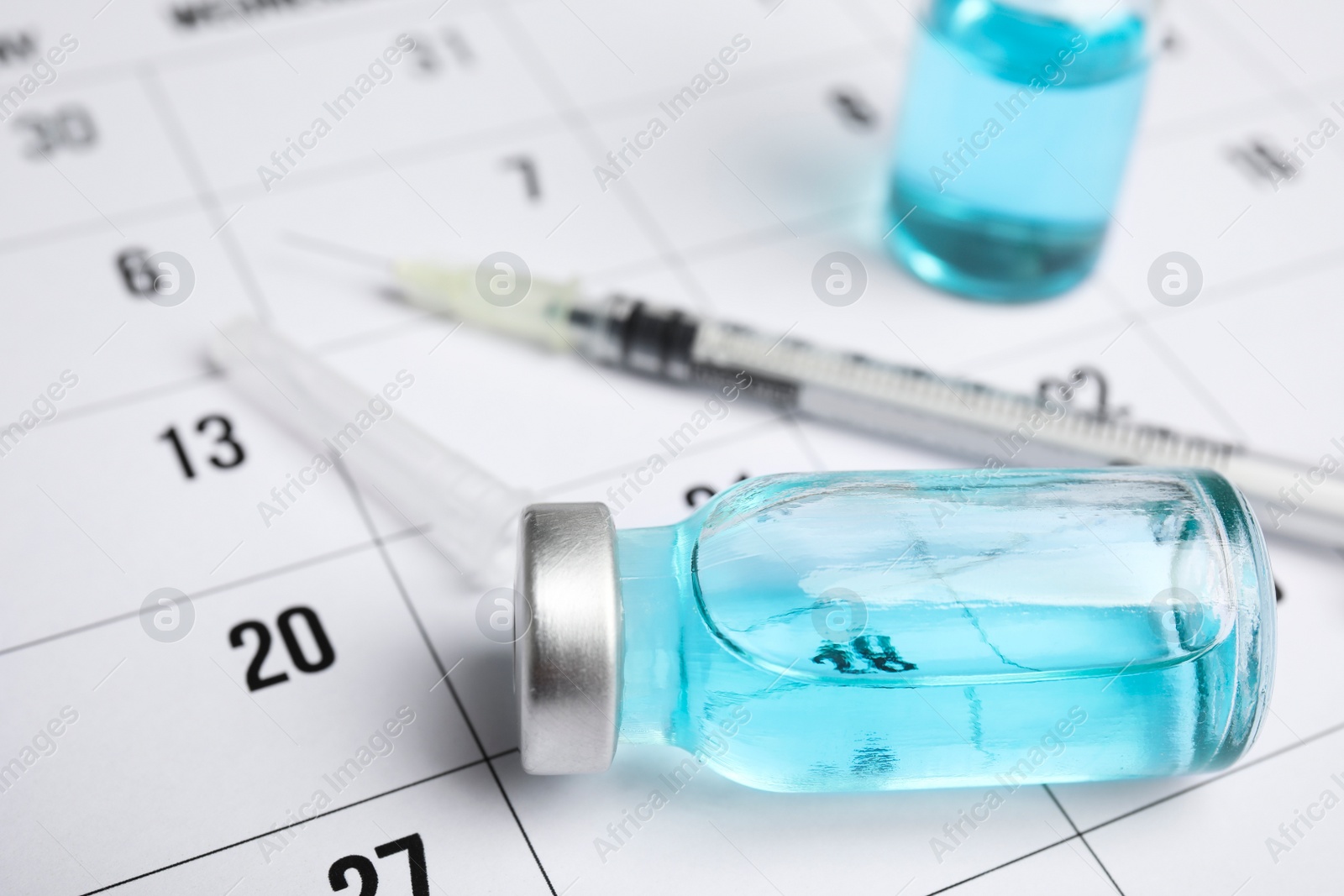 Photo of Vial and syringe on calendar, closeup. Vaccination and immunization