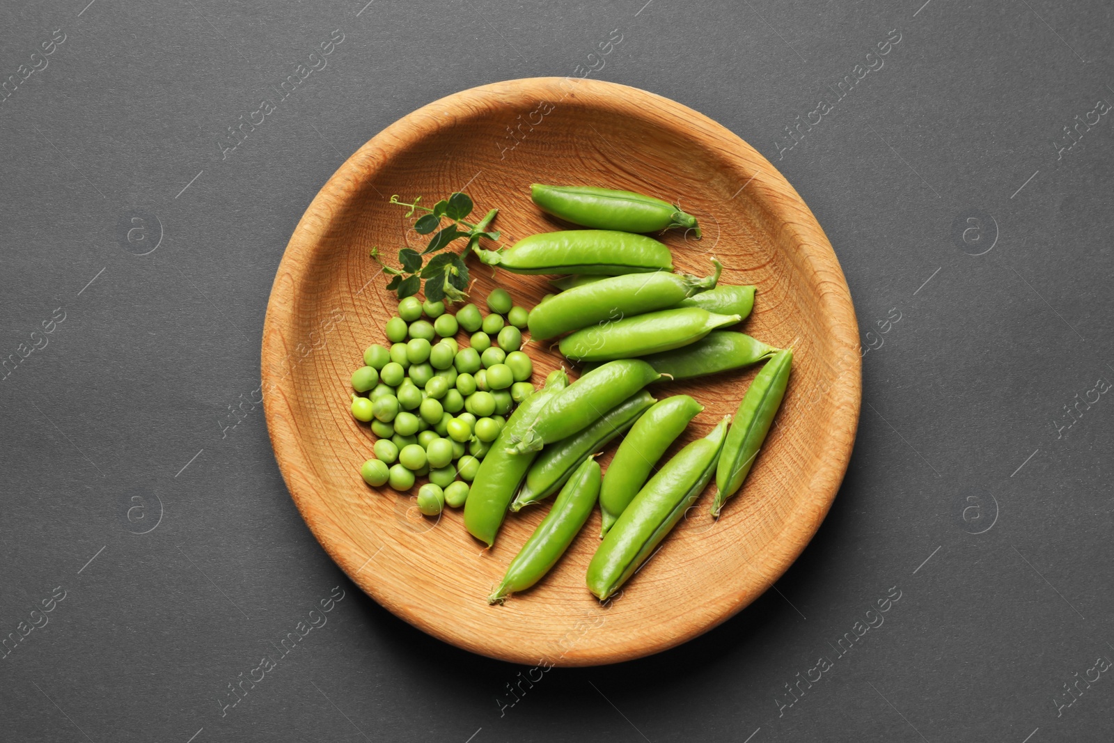 Photo of Plate with green peas on black background, top view