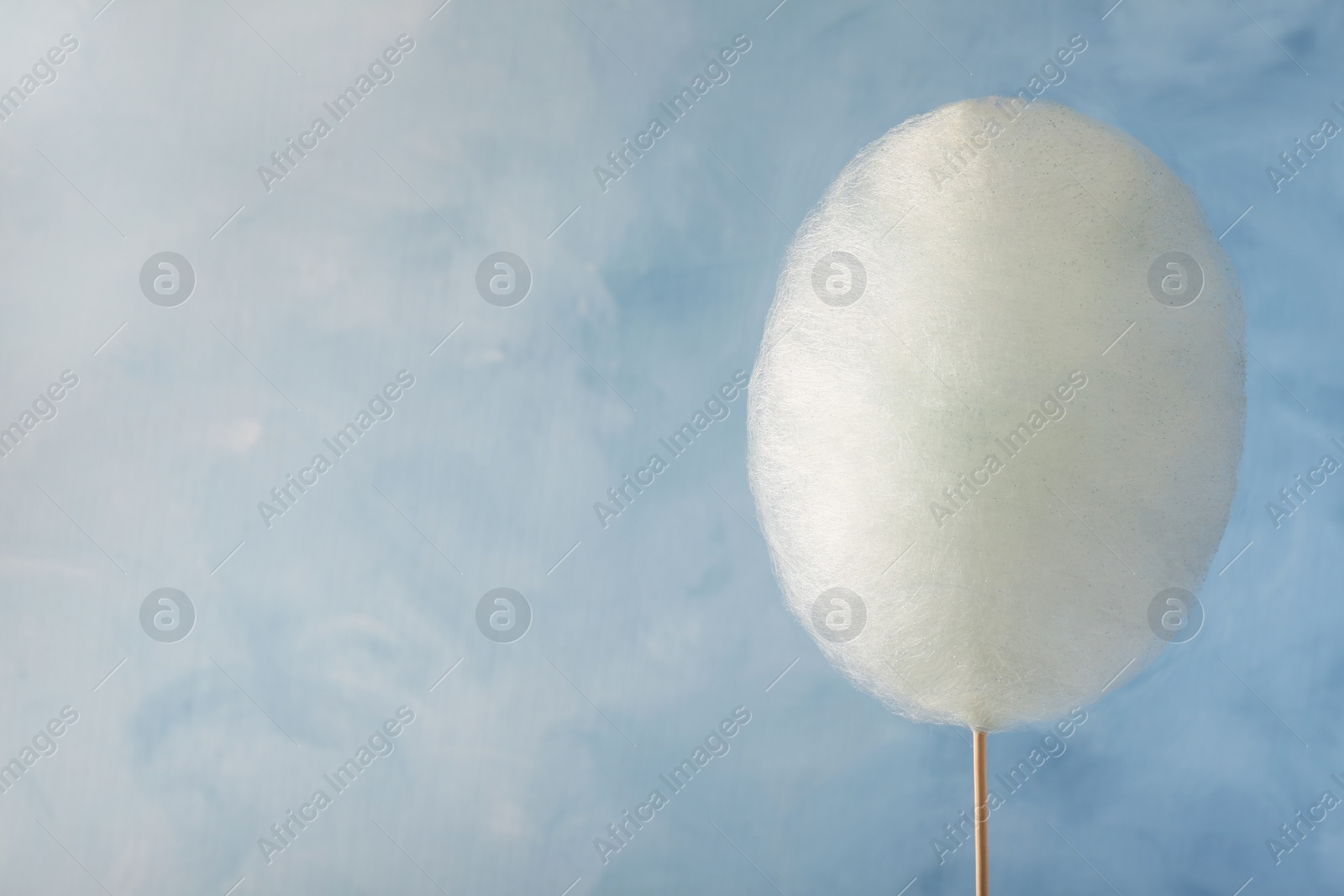 Photo of One sweet cotton candy on light blue background, space for text