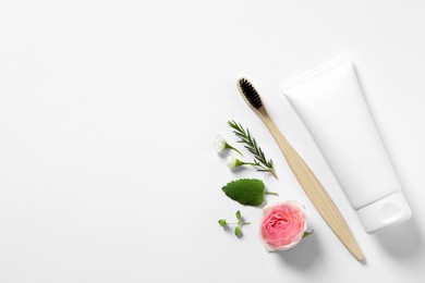 Flat lay composition with toothbrush, toothpaste, herbs and flowers on white background. Space for text