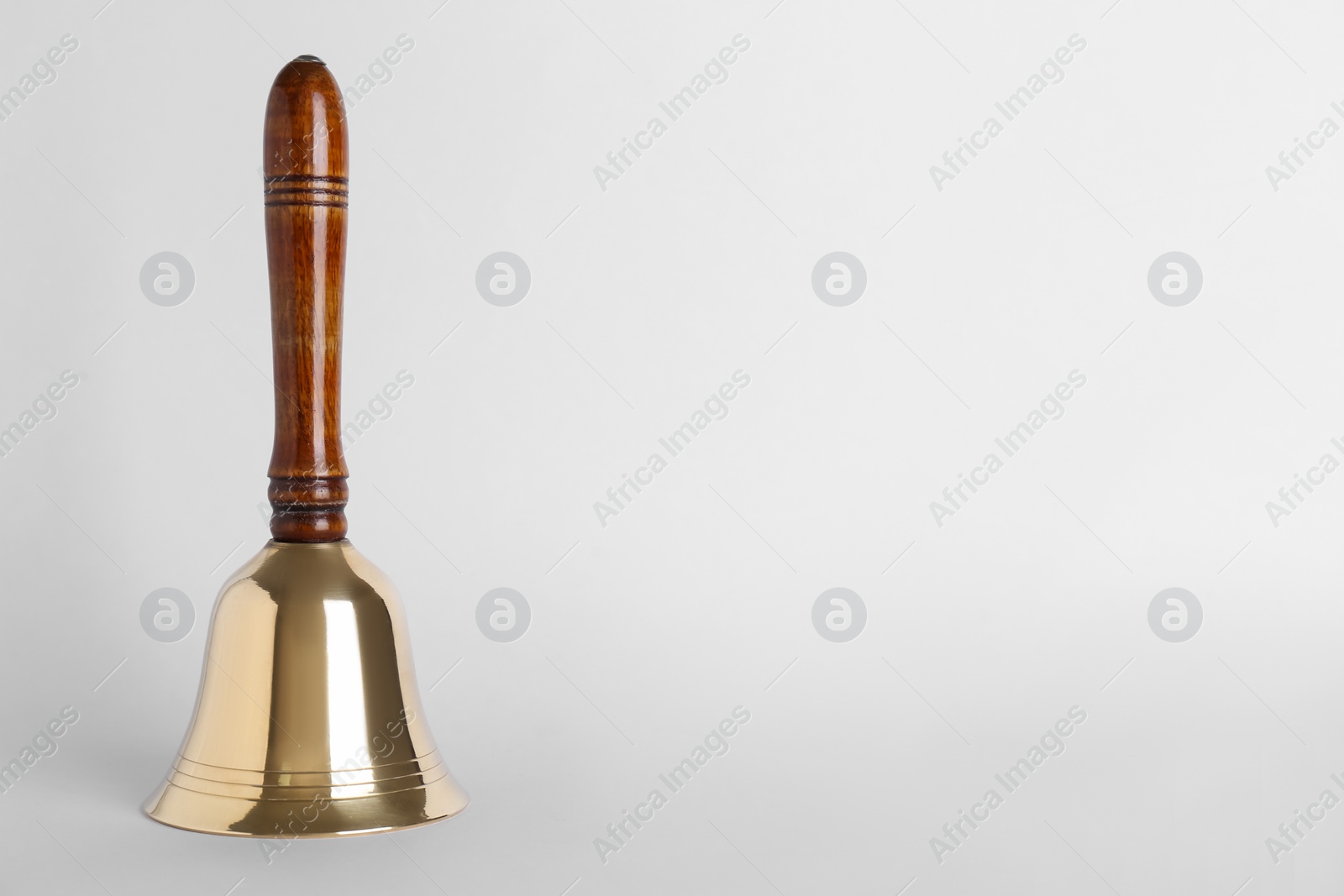 Photo of Golden school bell with wooden handle on grey background. Space for text