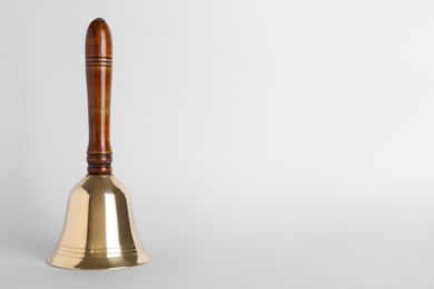 Photo of Golden school bell with wooden handle on grey background. Space for text