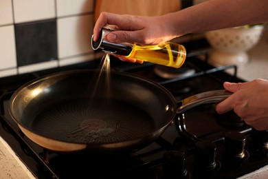 Photo of Vegetable fats. Woman sprinkling oil into frying pan on stove, closeup
