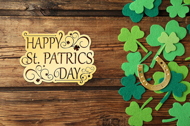 Image of Flat lay composition with clover leaves and horseshoe on wooden background. St. Patrick's day