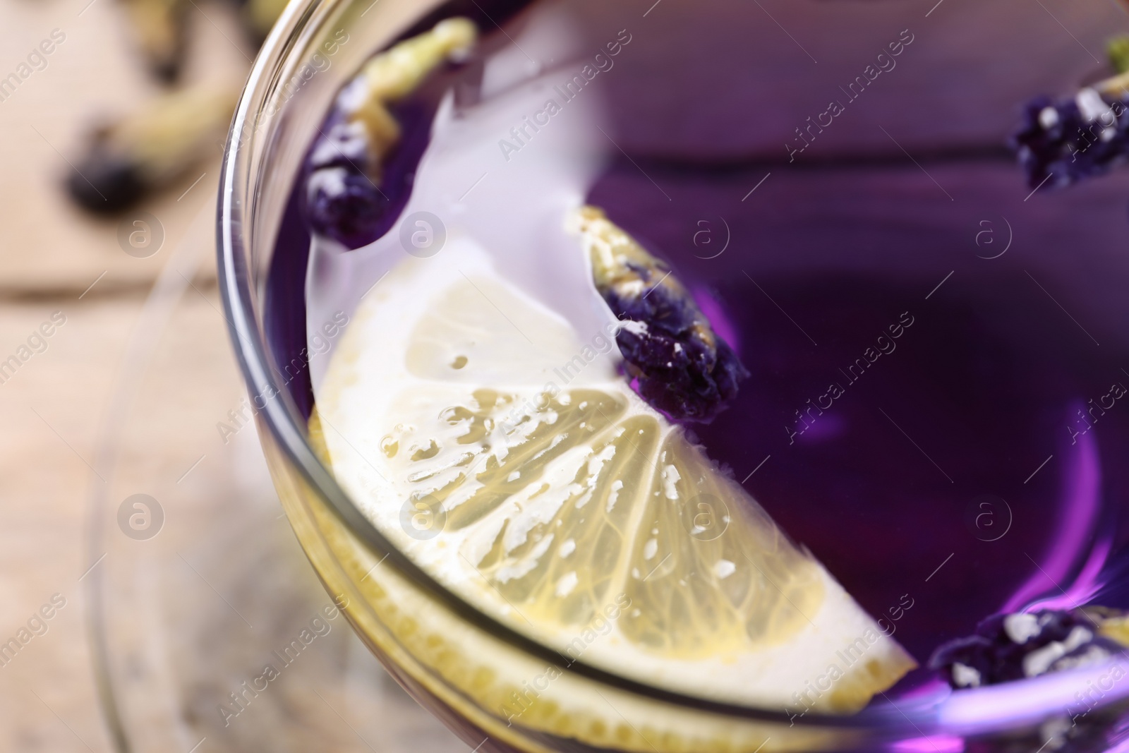 Photo of Glass cup of organic blue Anchan with lemon, closeup. Herbal tea