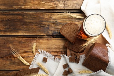 Photo of Flat lay composition with delicious kvass, spikes and bread on wooden table, space for text