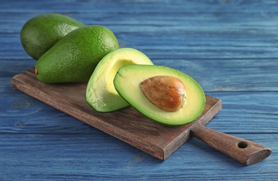 Board with ripe avocados on wooden background