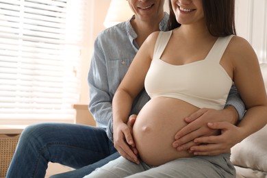 Photo of Man touching his pregnant wife's belly at home, closeup