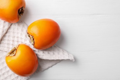 Photo of Delicious ripe persimmons on white wooden table, top view. Space for text