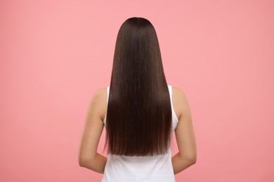 Woman with healthy hair after treatment on pink background, back view