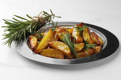 Plate with tasty baked potato and aromatic rosemary on white marble table