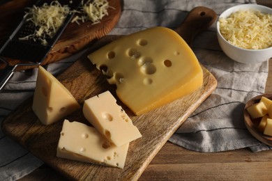 Photo of Grated, cut cheese and grater on wooden table