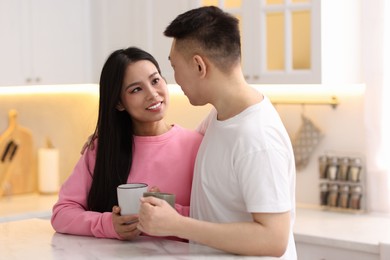 Photo of Lovely couple with cups of drink enjoying time together in kitchen