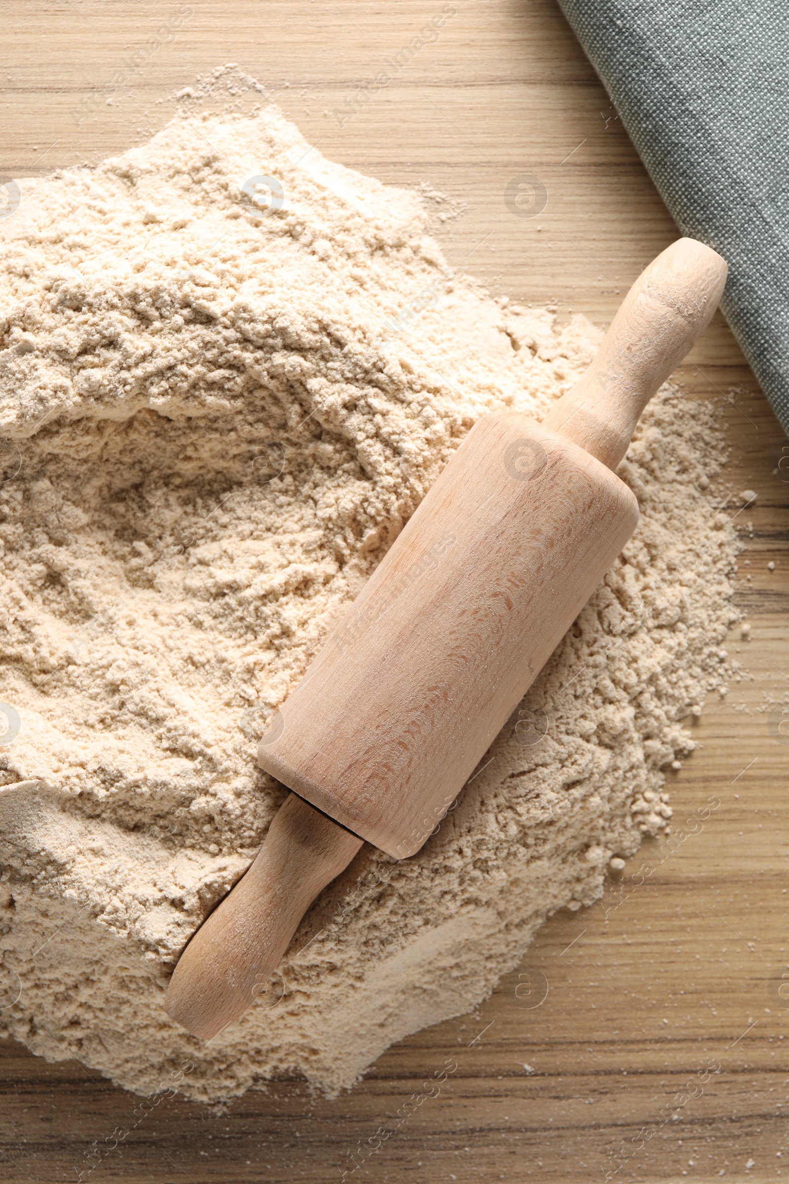 Photo of Pile of flour and rolling pin on wooden table, top view