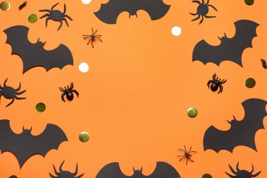 Frame made with Halloween decor on orange background, flat lay. Space for text