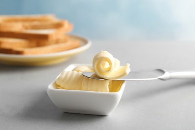 Photo of Knife and gravy boat with butter curls on table